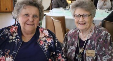 two elderly women sit at a table