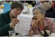 two women stare at a a page with photos