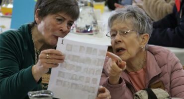 two women stare at a a page with photos