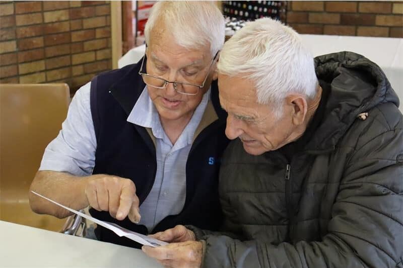 Two men stare at a a page with photos