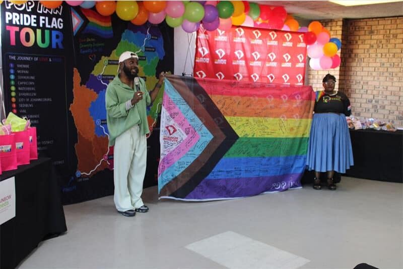 two people hold up a rainbow flag