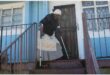 old woman with crutches at the top of a flight of stairs