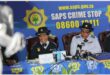 two police women sit in front of a police banner
