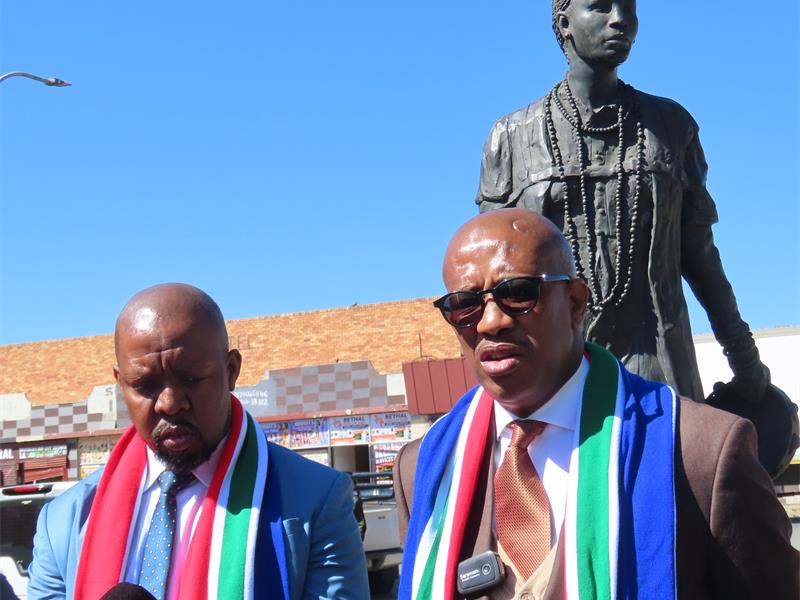 Two men with the SA flag colours scarves with a statue in the background