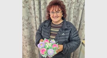 a woman holding a bouquet of cupcakes