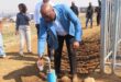 a man pours water into a glass from a tap outside