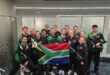 a team wearing the same tracksuits hold up a SA flag