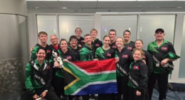 a team wearing the same tracksuits hold up a SA flag