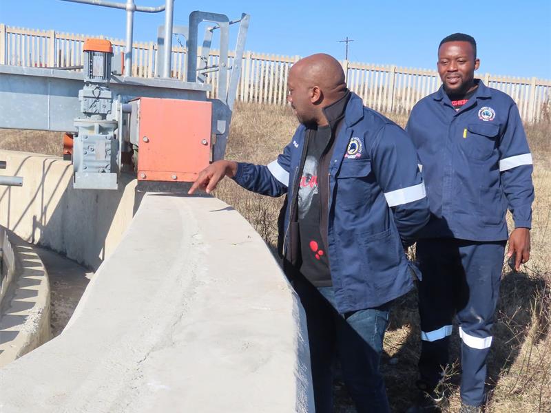 two men inspect a water dam