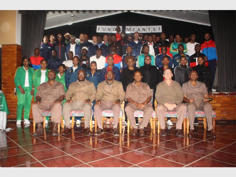 a large group of people behind a row of prison wardens