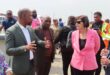 a man in a suit speaks to a woman in a pink jacket