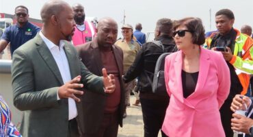 a man in a suit speaks to a woman in a pink jacket