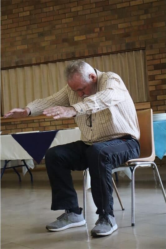 elderly man in chair stretches forward