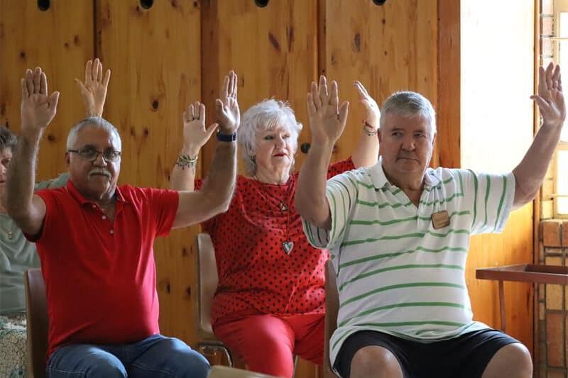 old people sit in chairs and exercise