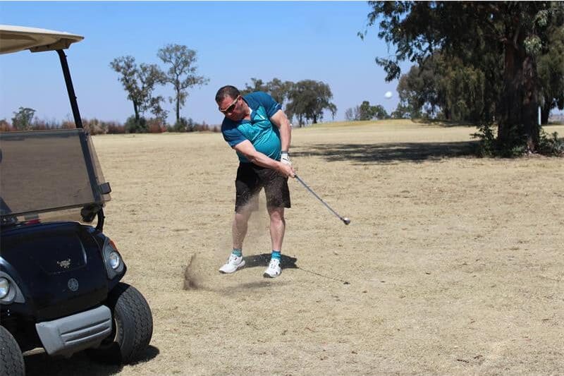 a man in a blue shirt tees off