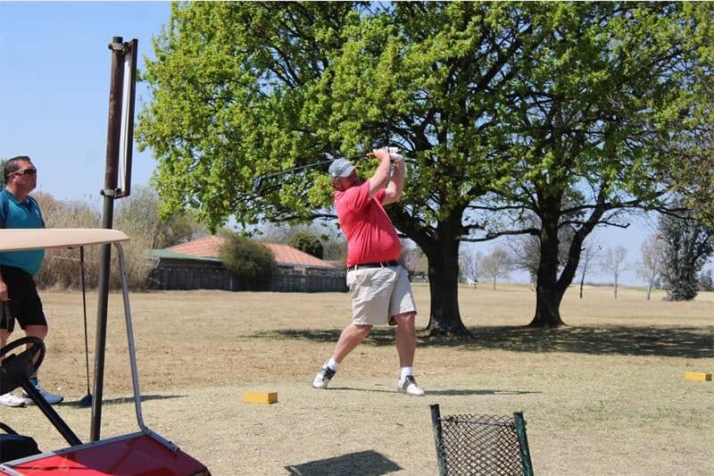 man in a red shirt plays golf