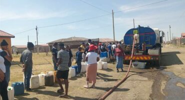people queue for water from a water tanker