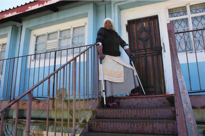 old woman with crutches at the top of a flight of stairs
