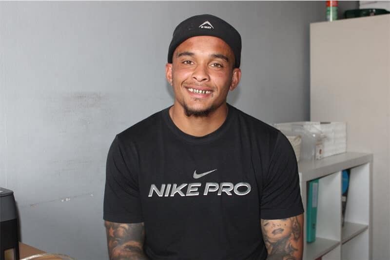 a man in black with a cap smiles