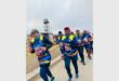 Athletes in blue and yellow outfits run in the road