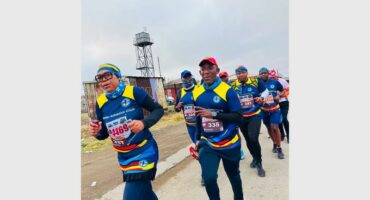 Athletes in blue and yellow outfits run in the road