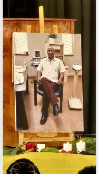 photo of a man placed on a stand in the front of a hall