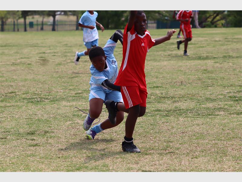a soccer player in light blue runs after a player in red