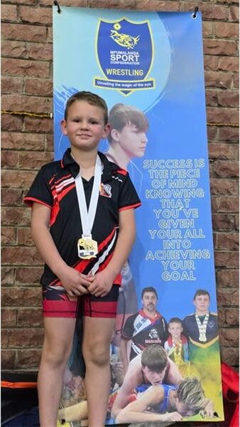 boy in a wrestling suit with a medal around his neck