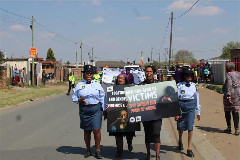 police women hold up posters while they walk in the street