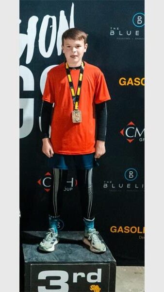 a boy with an orange t-shirt stnds on a podium