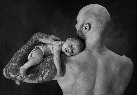 a man holding a newborn baby on his shoulder