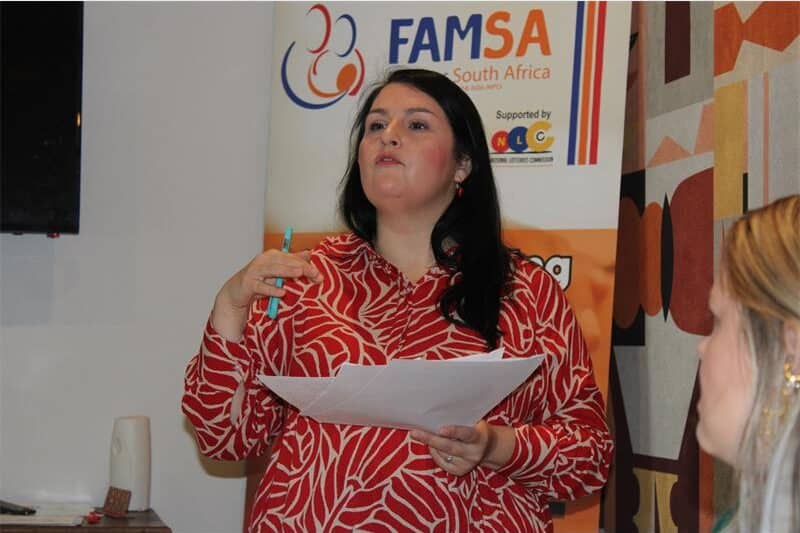 a dark haired woman is speaking and holding papers in her hands