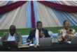 three people sitting at a long table on the stage