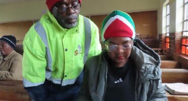 a man in a reflector jacket looks over a woman's shoulder