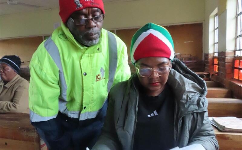 a man in a reflector jacket looks over a woman's shoulder