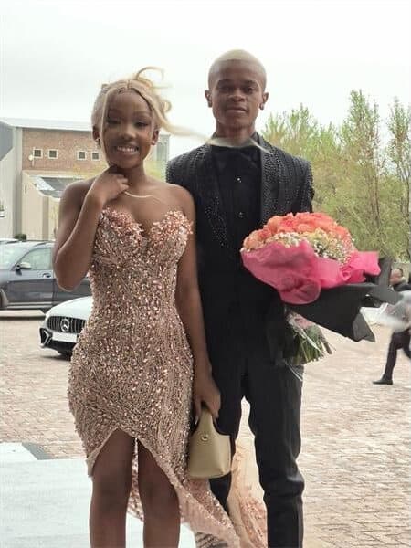 A young couple is dressed to the tee with flowers in the girls arms