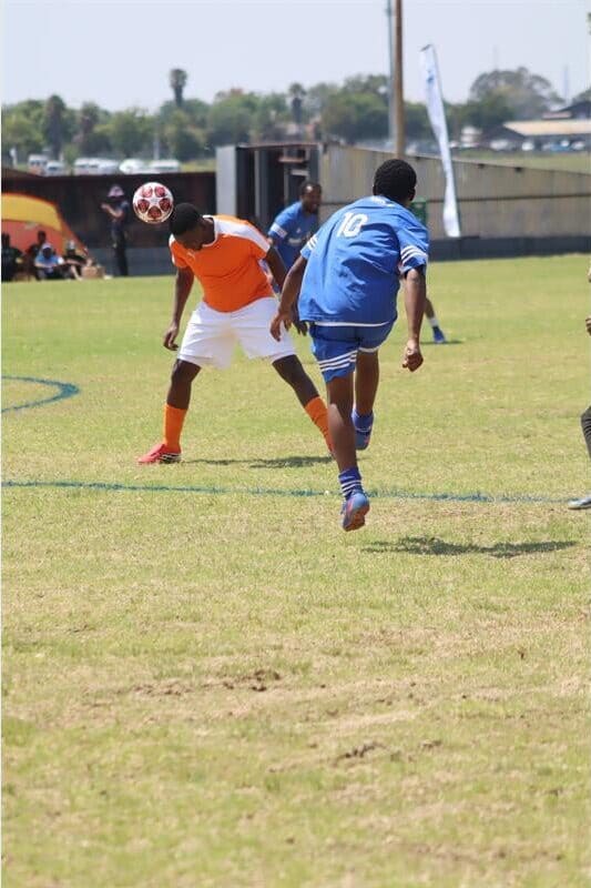 a soccer player with an orange shirt headbuds the ball