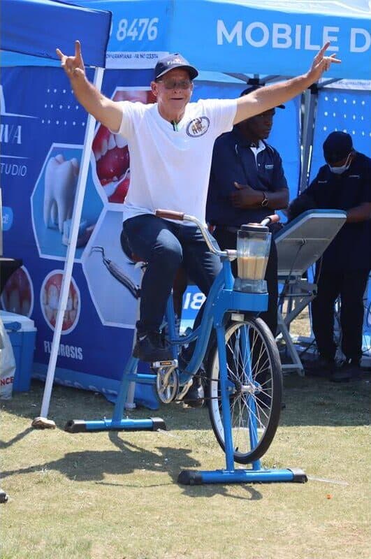 a man paddling a stationary bicycle shows peace signs