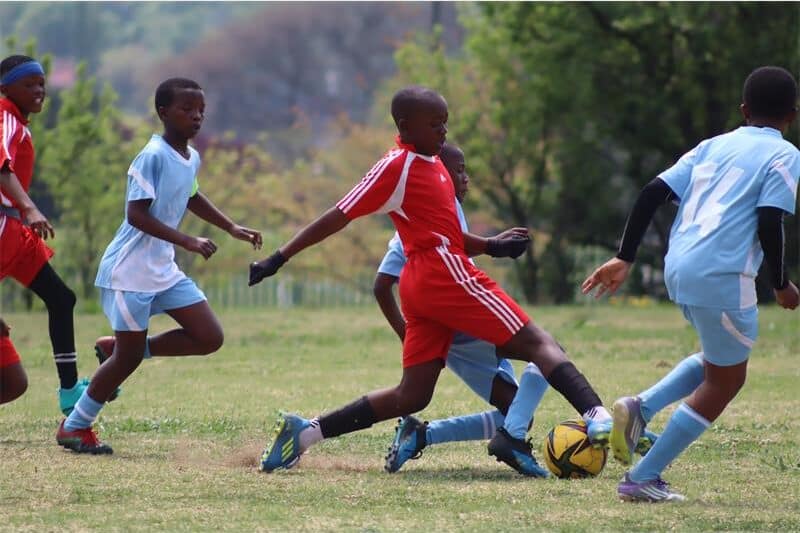 s soccer player in light blue compete against players in red
