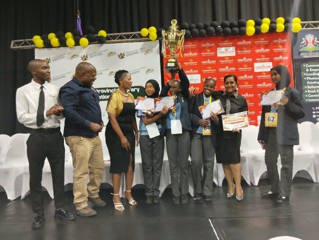 learners and teachers hold up a cup on stage