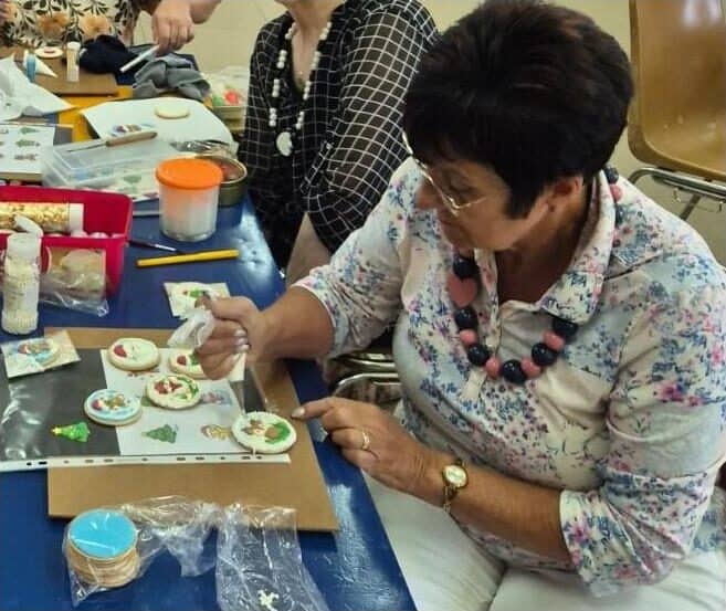 a woman decorates a Christmas cookie