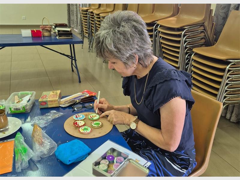 a woman decorates a Christmas cookie