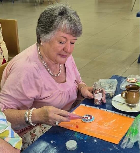 a woman decorates a Christmas cookie