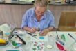 a woman decorates a Christmas cookie