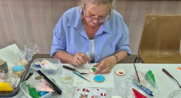 a woman decorates a Christmas cookie