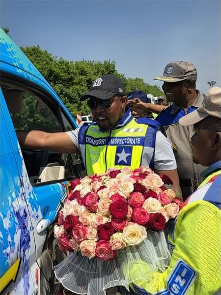 a traffic officer gives roses to women in a minibus