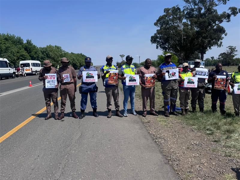 men with posters stand in a row on the side of the road