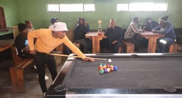a man in orange jersey playing pool