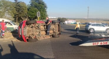 A man stands on a toppled over car